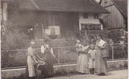 Altes Bauernhaus mit Bauersleute davor.