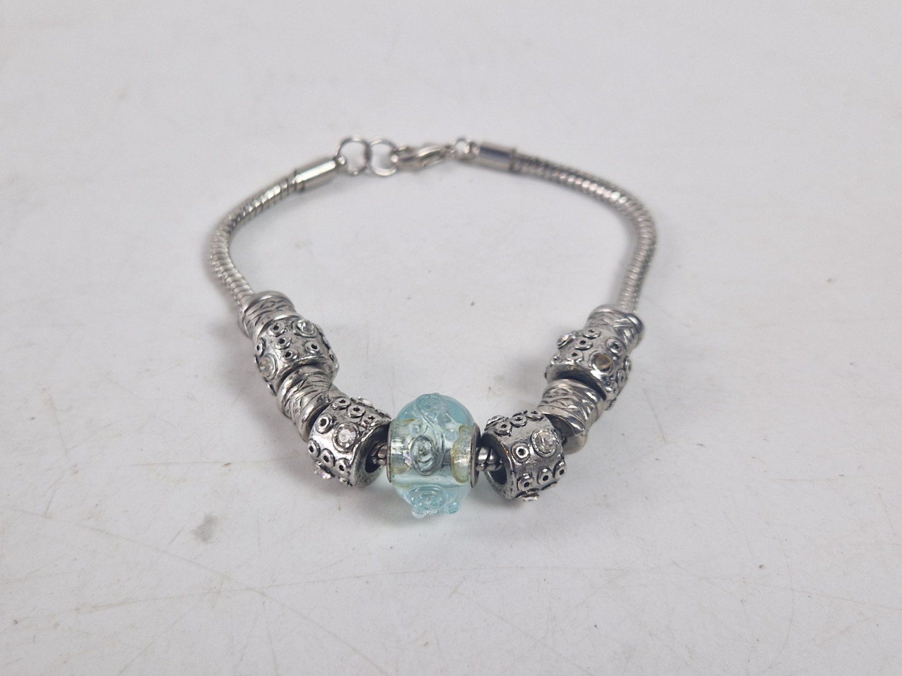 Bracciali & Braccialetti: Armband silberfarben mit Charms und blauem Glas-Element – Usato da Muhen venduto da Restwert_Muhen 1