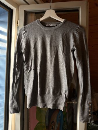 Grauer Pulli eng mit goldenen Knöpfen