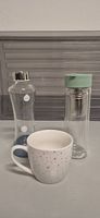 3 Trinkgefässe: Tasse, Wasserflasche, Teeflasche