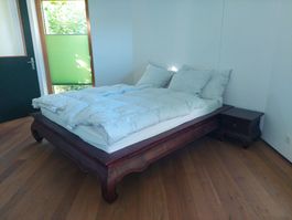 Massivholz-Bettgestell im Asia-Stil mit Nachttisch.