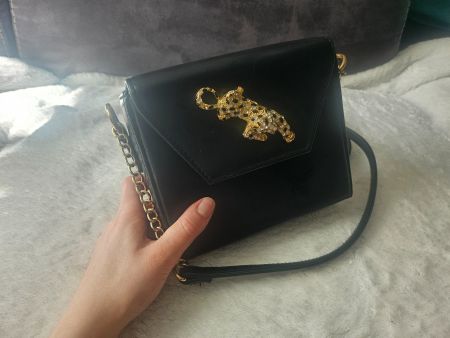 Schicke schwarze Umhängetasche mit goldenem Panther-Anhänger