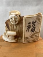 Netsuke, sitzender Mann mit Tafel, signiert
