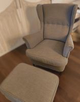 Eleganter grauer Ohrensessel mit passendem Hocker
