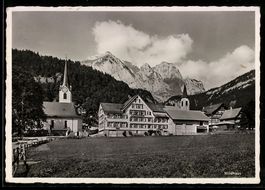 AK Wildhaus, Ortspartie mit Kirchen und Hotel vor Bergpanora