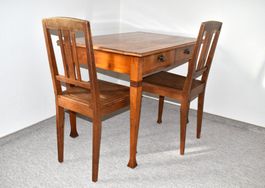 Schöner antiker Holztisch mit Schubladen und Stühlen