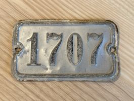 Altes Metallschild mit Nummer 1707 in gebrauchtem Zustand