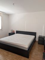 Schwarzes Holzbett mit Matratze und zwei Nachthästli
