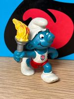 Fackelträger-Schlumpf mit UK-Emblem auf der Brust