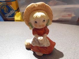 Figur Mädchen sitzend, grosser Hut, rote