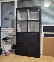 Kallax-Regal schwarz mit 4 Glasvitrinen und 4 Stoffboxen.
