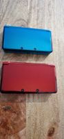 2 Nintendo 3DS Konsolen blau und rot mit einem Ladekabel