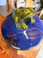 grüner Frosch auf blauem Keramikstein
