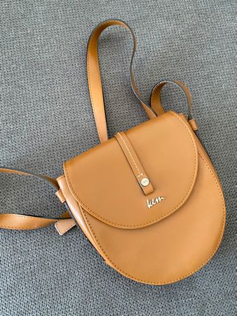 Eine kleine, sandfarbene Damenhandtasche.