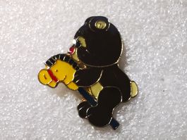 Ansteckpin 23: Teddybär auf Schaukelpferd