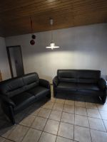 Zwei schwarze Ledersofas