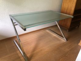 Bureau en verre avec pieds en métal.