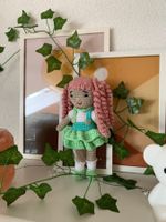 Handgestrickte Puppe im Kleid mit lockigen Haaren