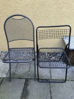 Zwei verschiedene schwarze Klappstühle, Metall