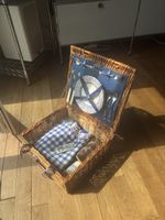 Picnic basket with tableware and checkered blanket
