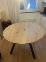 Runder Holztisch mit schwarzem Dreibein-Gestell