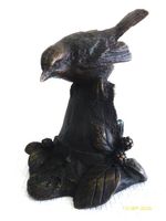 Hübscher kleiner Vogel aus Bronze auf Baumstrunk.