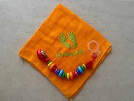 Orange Musselintuch mit Schnullerkette und Fusspuren (Uni...