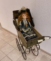 Antiker Puppenwagen mit Porzellankopfpuppe.