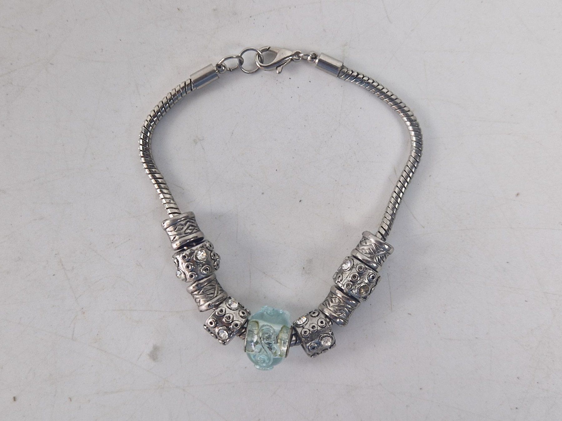 Bracciali & Braccialetti: Armband silberfarben mit Charms und blauem Glas-Element – Usato da Muhen venduto da Restwert_Muhen