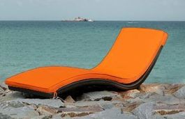 Rattan Liege mit orangem Kissen