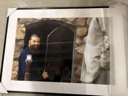 Gerahmtes Foto: Priester im Gemäuer lächend