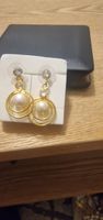 Elegante Ohrringe mit Perlen und Strass, die goldfarben.