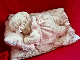 Süsse Schlafpuppe auf Kissen im KInderwagen