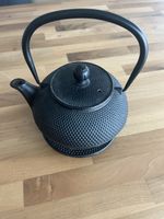 Schwarze Teekanne aus Gusseisen mit Sieb und Untersetzer