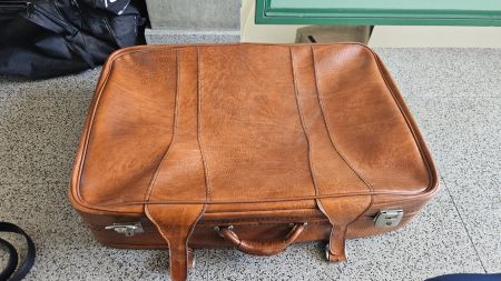 Vecchia valigia di pelle marrone con rotelle posteriori