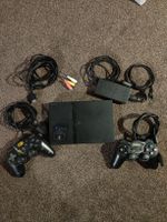 Playstation 2 slim Konsole mit Spielen und Lenkrad.