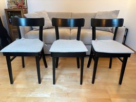Schwarze Holzstühle mit grauen Sitzkissen