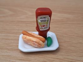 Hotdog mit Essiggurke und Heinz Ketchup auf Keramik Teller