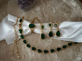 Ensemble de bijoux dorés avec pierres vertes émeraude.