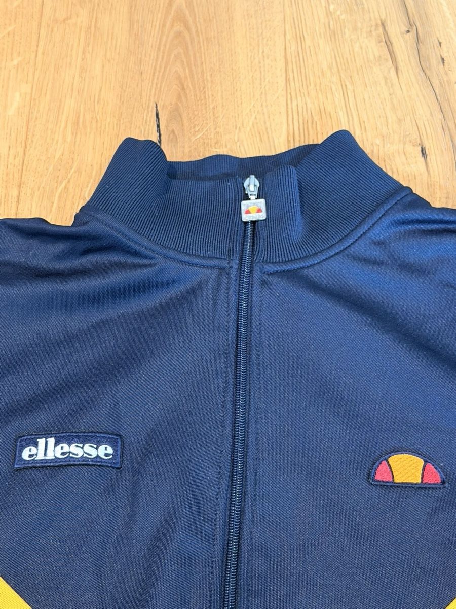 Ellesse Giacche: Ellesse navy blue track jacket with yellow and red diagonal  – Usato da Pfaffhausen venduto da placard 2