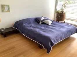 Doppelbett mit Kissen und Bettdecke plus Nachttisch
