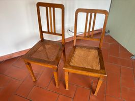 Zwei Holzstühle mit geflochtener Sitzfläche
