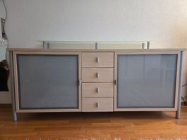 Hohes Sideboard aus hellem Holz und Glaselementen