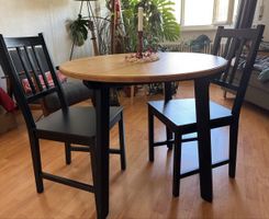 Table ronde en bois clair + 2 chaises noires