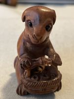 Netsuke Holz, sitzendes Tier mit Korb, signiert