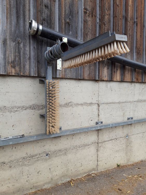 Mounted livestock grooming brush installed on barn wall