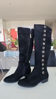 Bottes hautes en daim noir avec élément décoratif.