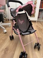 Poussette pour poupée rose avec motif papillon.