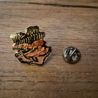 Pin’s artistique – skyline ville et main – émail noir/or/rou