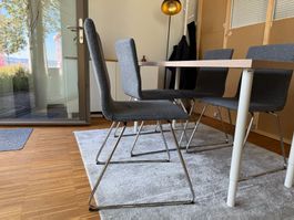 4 graue Polsterstühle mit Metallgestell
